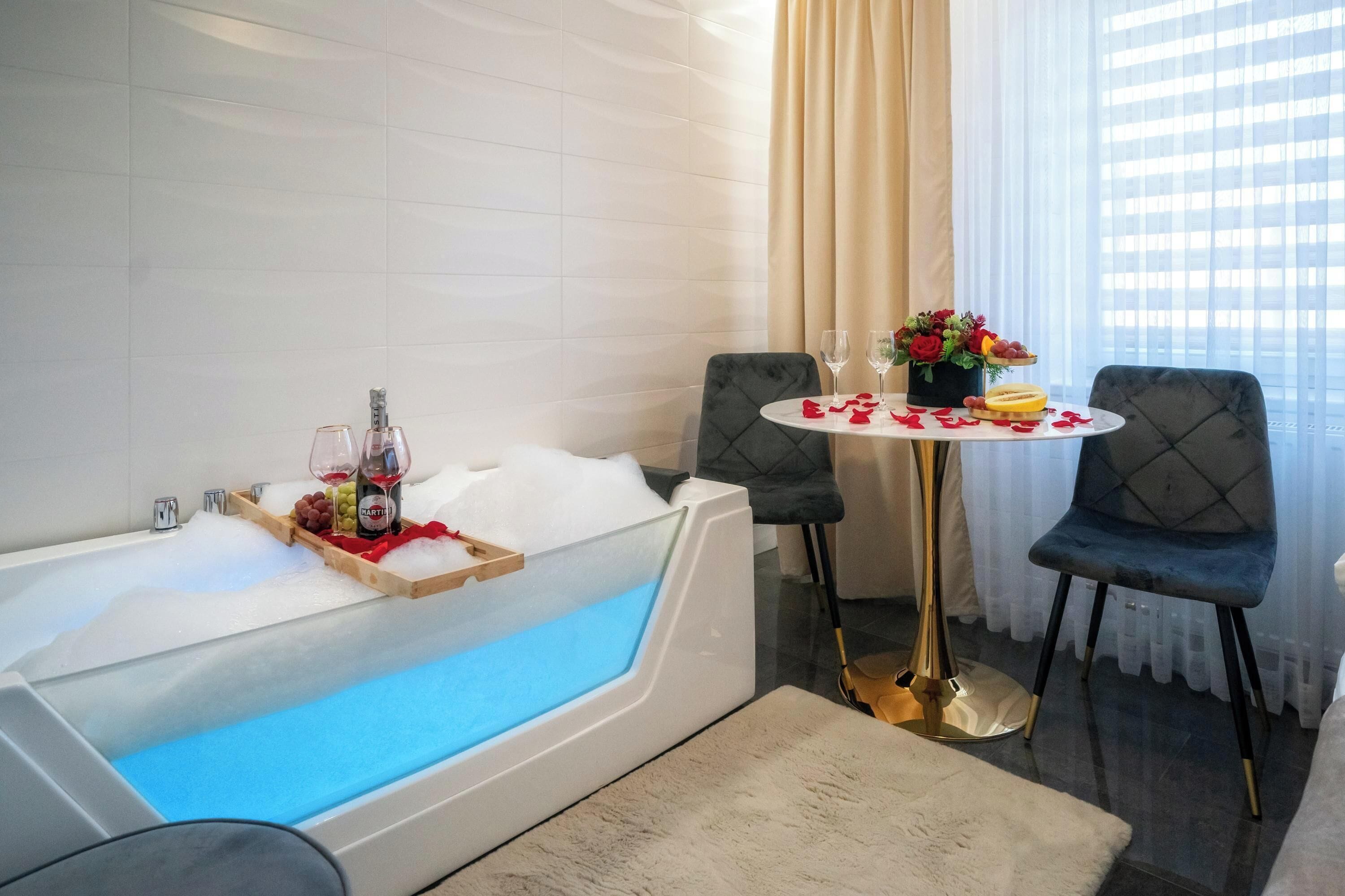 Un baño moderno con una bañera grande, una mesa redonda con sillas y un jarrón de flores.