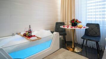 Un baño moderno con una bañera grande, una mesa redonda con sillas y un jarrón de flores.