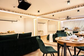 A modern dining area with a round table set for a meal, green upholstered seating, and a decorative ceiling design. - Górski Resort Zakopane (Poronin)