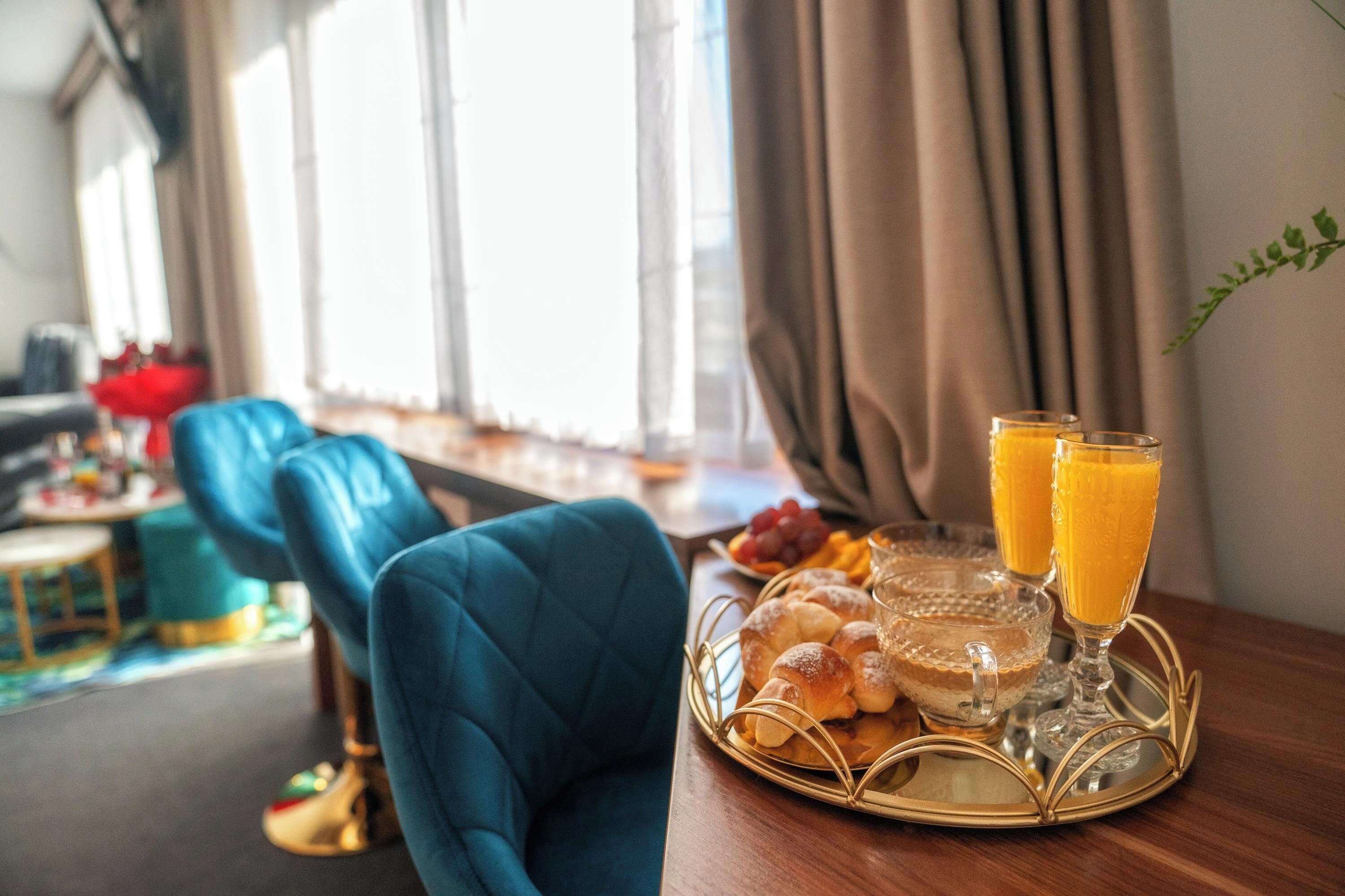 A dining area with a table set for breakfast, including bread, fruit, and orange juice.