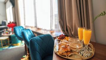 A dining area with a table set for breakfast, including bread, fruit, and orange juice.