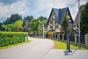 A Gorski Resort with a prominent building featuring a steep roof and a balcony. - Górski Resort Zakopane (Poronin)