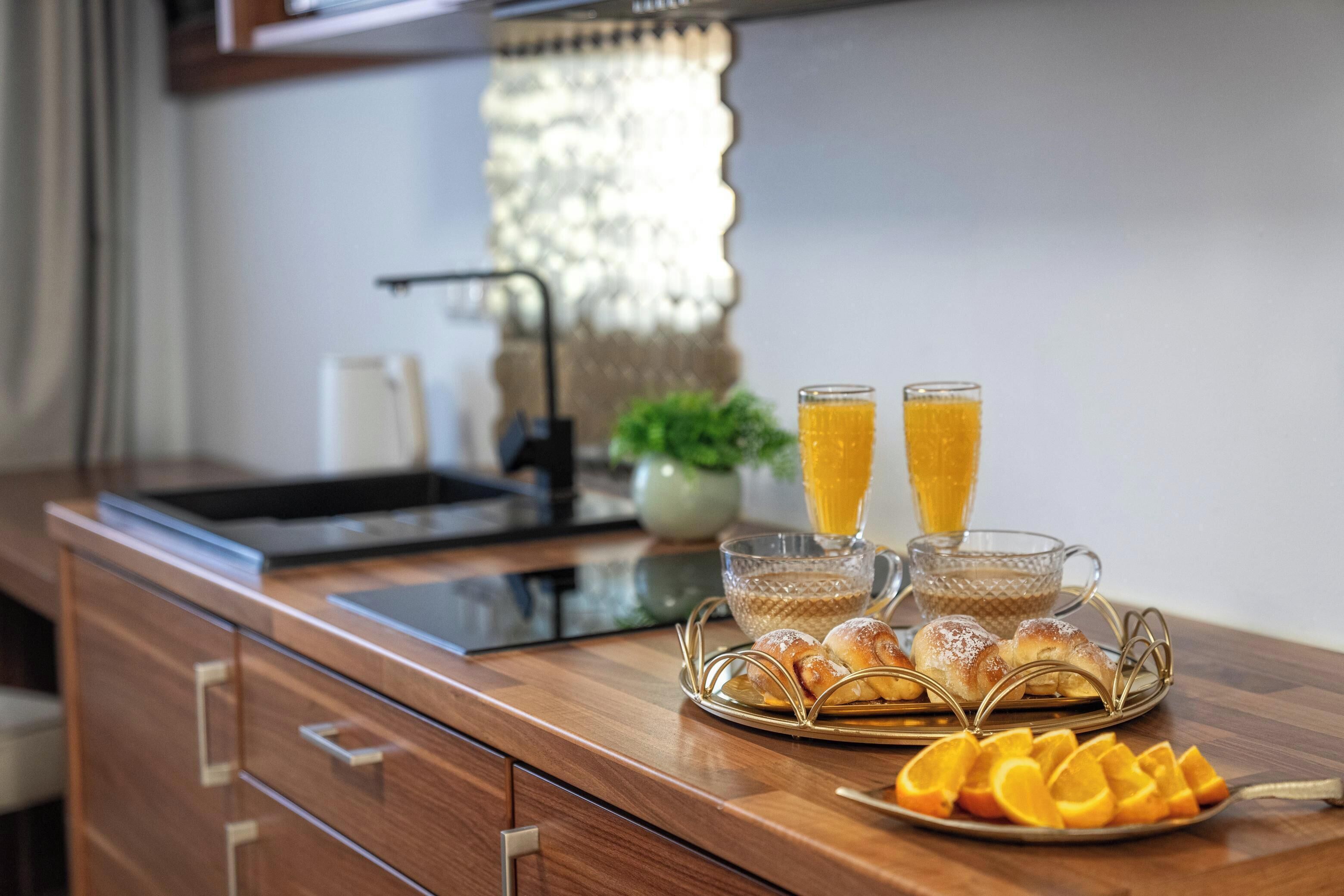 Desayuno con pasteles, rodajas de naranja y dos vasos de zumo de naranja sobre una mesa de madera.