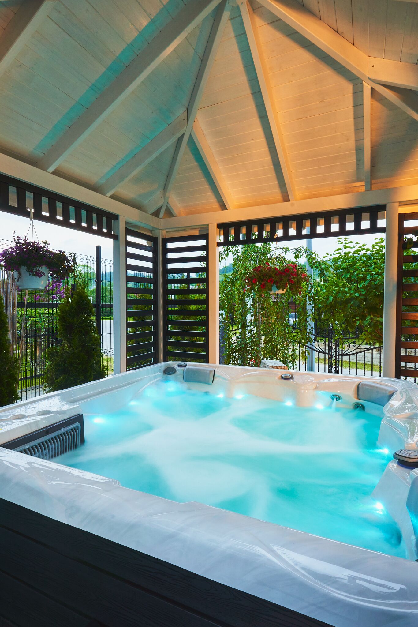 A hot tub under a covered area with a view of greenery.