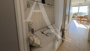 A bedroom with a bed, a bedside table, and a window. - REZ DE CHAUSSEE, 1ERE LIGNE MER, ACCES DIRECT PLAGES (Sète)