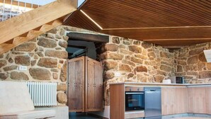 Une cuisine avec des murs en pierre, des armoires en bois et un four encastré.