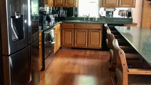 Una cocina con armarios de madera, electrodomésticos de acero inoxidable y encimera de granito.
