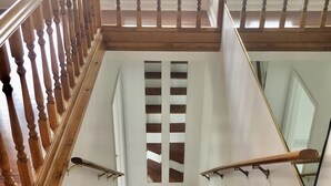 Una escalera de madera con barandilla y un vidrio en la parte inferior.