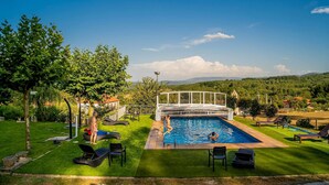 A swimming pool with a glass bridge, surrounded by a well-maintained lawn and lounge chairs. - A Forxa - Casa Ferrador (Ribeira Sacra) (Bolmente)