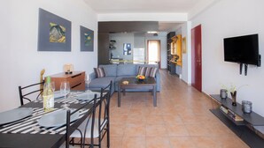 Un salon moderne avec une table à manger, un canapé et un téléviseur.
