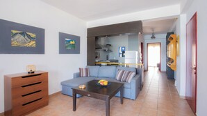 Un salon comprenant un canapé, une table basse, un meuble en bois et des œuvres d’art accrochées aux murs.