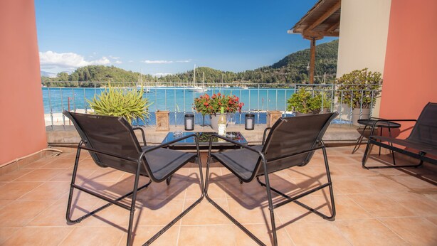 Une terrasse avec deux chaises et une table, donnant sur une étendue d’eau et des collines.