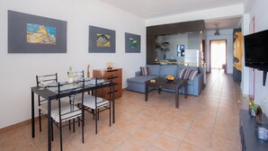 Un salon moderne avec une table à manger, un canapé et des œuvres d’art accrochées aux murs.