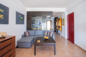 A modern living room with a sectional sofa, a coffee table with fruit, and a kitchen in the background. - Blue Seaview Apartment on Nydri Coast (Nydri)