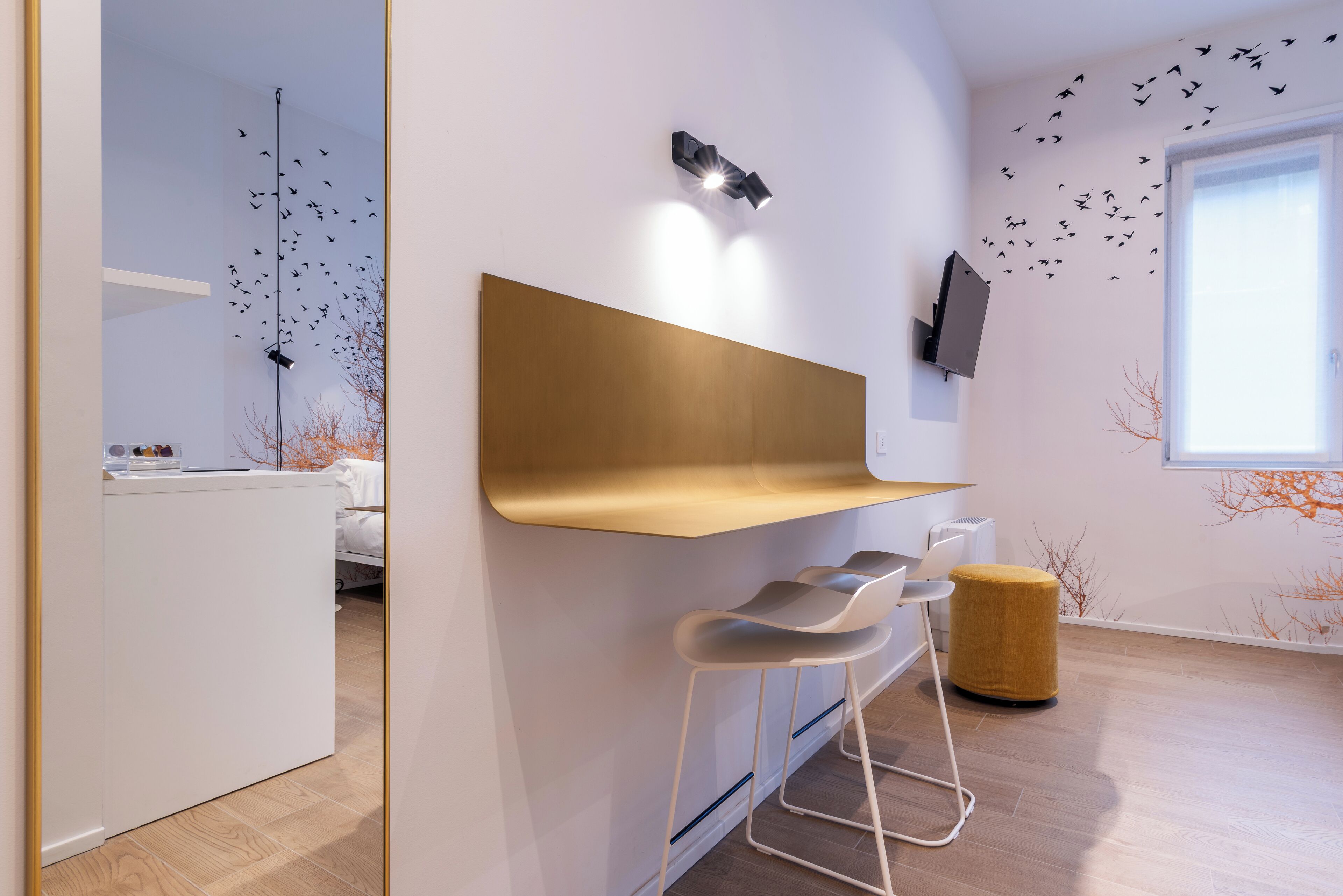 A modern kitchen with a wooden countertop, white bar stools, and a wall-mounted light fixture.