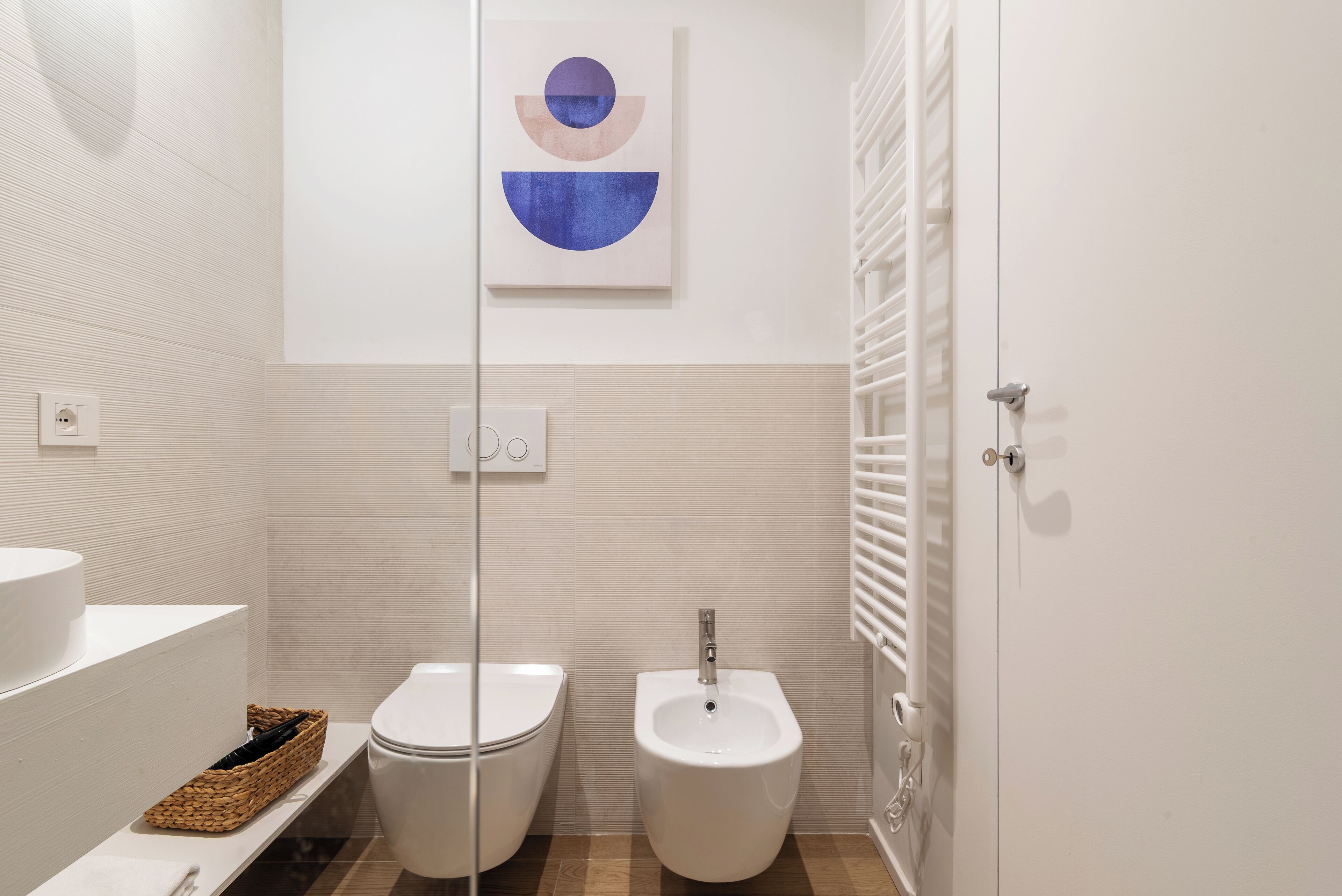 A modern bathroom with a toilet, bidet, and a white sink.