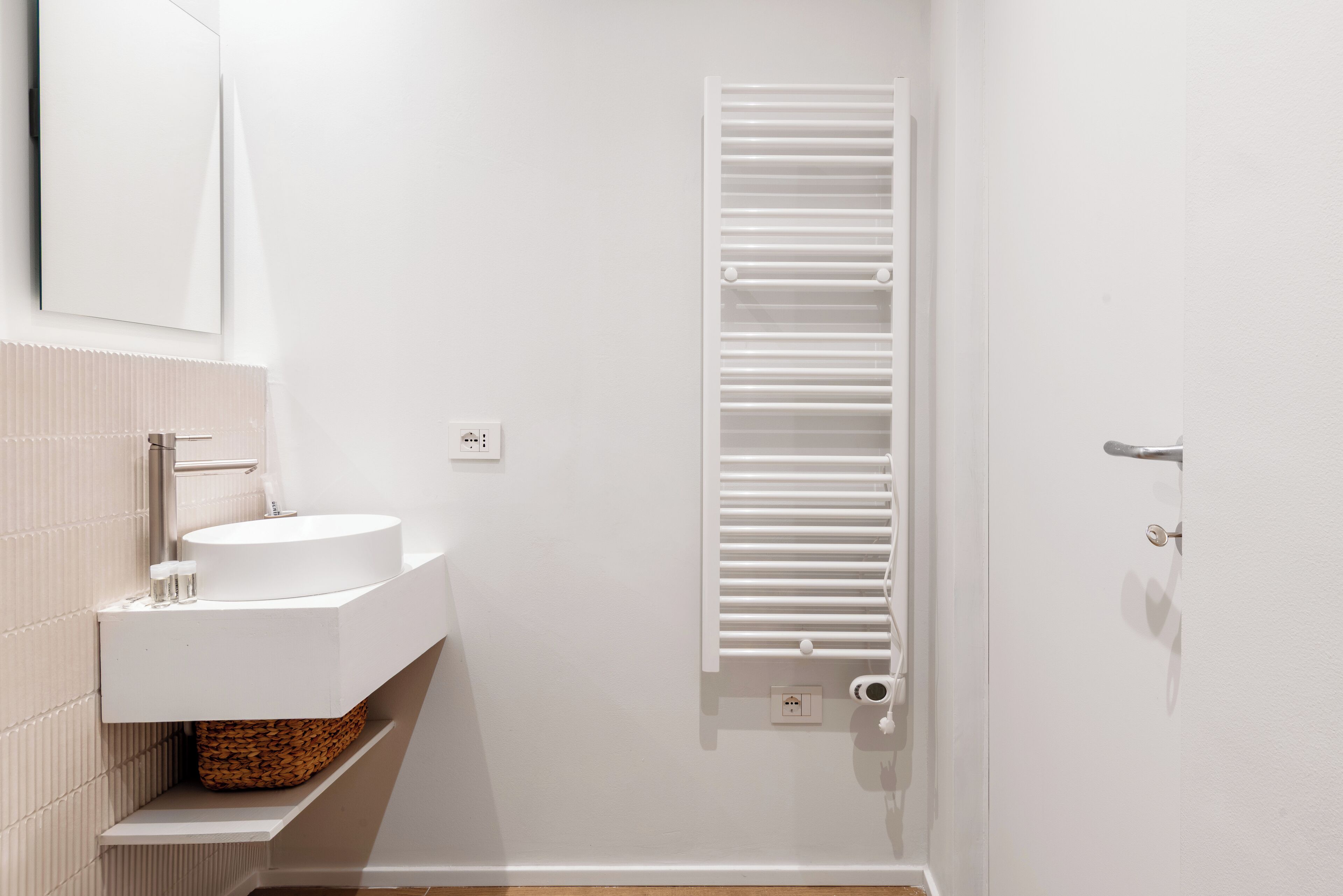 Un bagno moderno con lavandino, specchio e portasciuga in bianco.