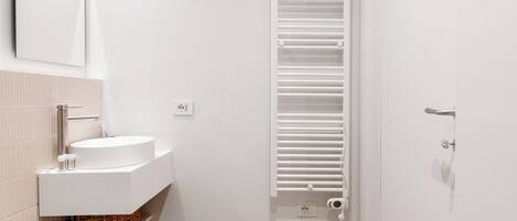 Un bagno moderno con lavandino, specchio e portasciuga in bianco.