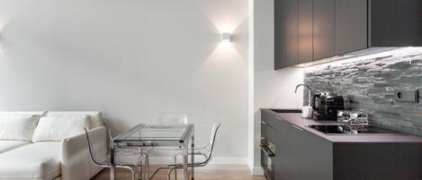 Una cocina moderna con protector contra salpicaduras de piedra, una mesa de comedor de vidrio y un sofá blanco.