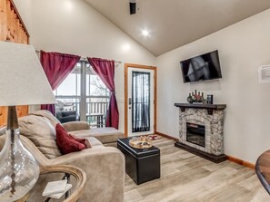 A living room with a sofa, a fireplace, a television, and a window with curtains.