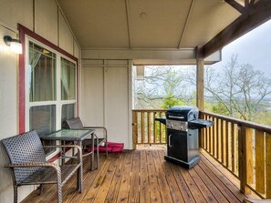 A covered outdoor area with a grill, wicker chairs, and a table.