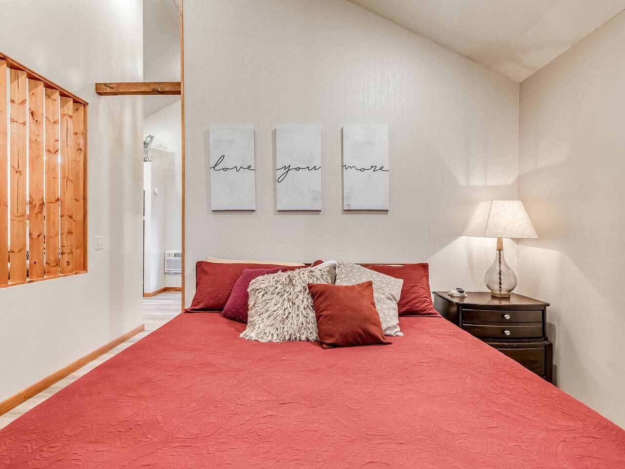 A bedroom with a large bed, a nightstand, a lamp, and three wall-mounted signs with text.