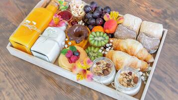 A tray of assorted food items including fruits, pastries, and a bottle of juice.