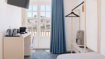 Una camera d'albergo con un letto, una scrivania con un computer, una macchina per il caffè e una TV.