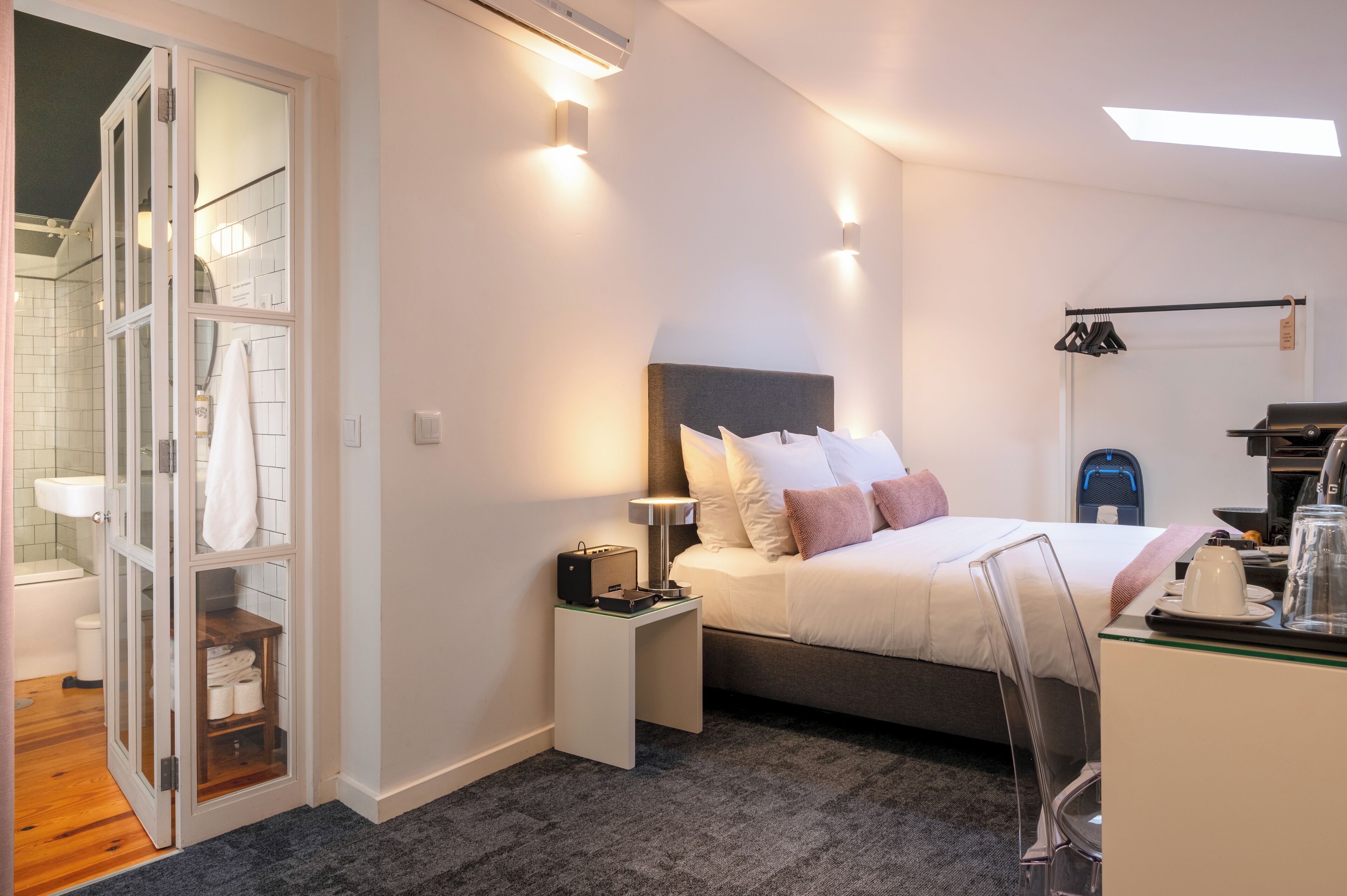 Une chambre d’hôtel moderne équipée d’un lit, d’une table de chevet et d’un dressing.