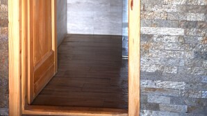 Una puerta de madera que da a un baño con pared de piedra y una toalla colgada.
