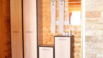 A wooden interior with a wardrobe, a small cabinet, and a mirror.