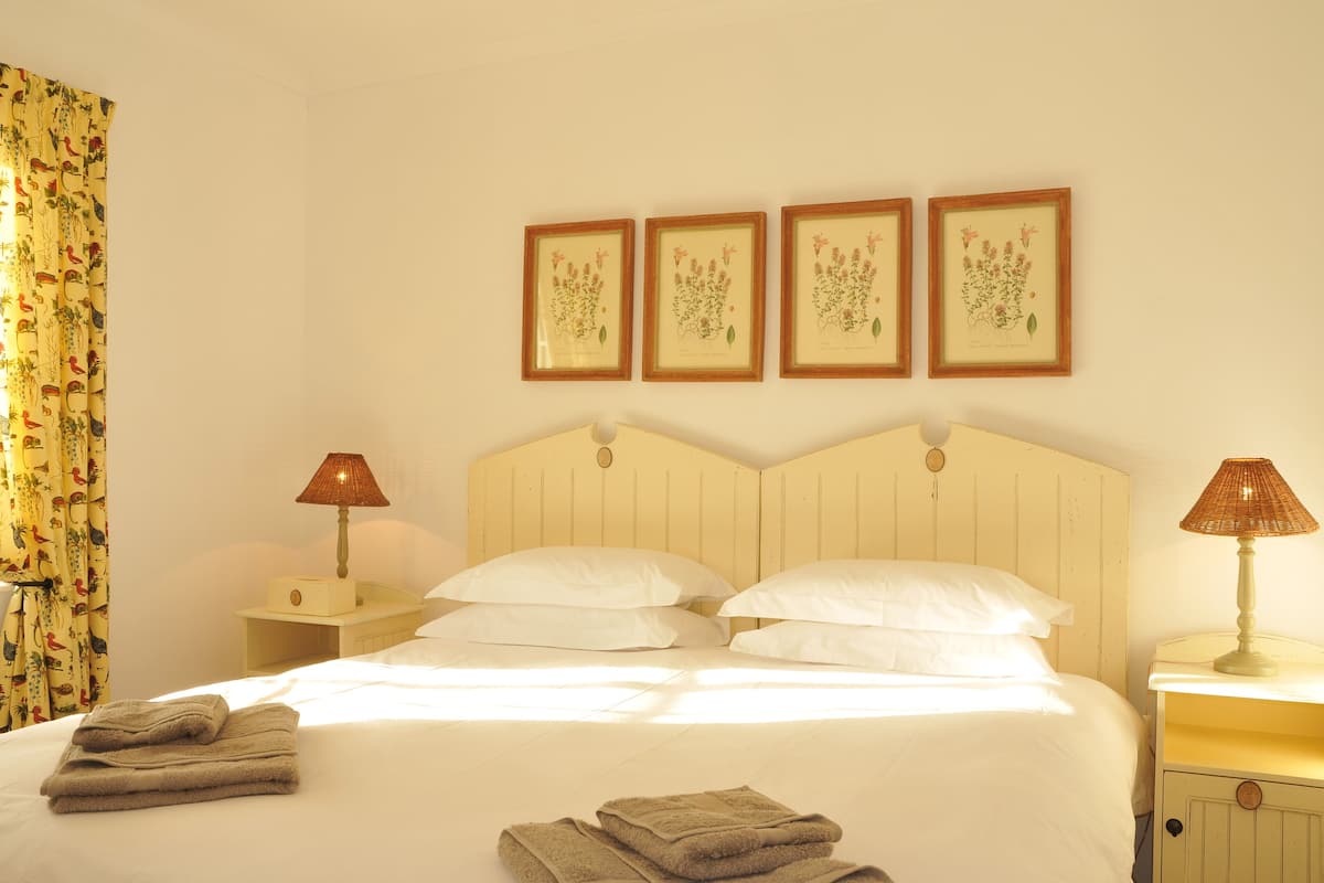 A neatly made bed with white linens, two bedside lamps, and a set of folded towels on the floor.