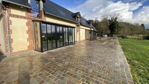 A modern building with a brick facade, large glass doors, and a paved patio area. - Villa l'Etable, 4 bedrooms (Trouville-sur-Mer)