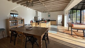 A spacious kitchen with wooden beams, a dining area with a large table and chairs, and a foosball table in the open space. - Villa l'Etable, 4 bedrooms (Trouville-sur-Mer)