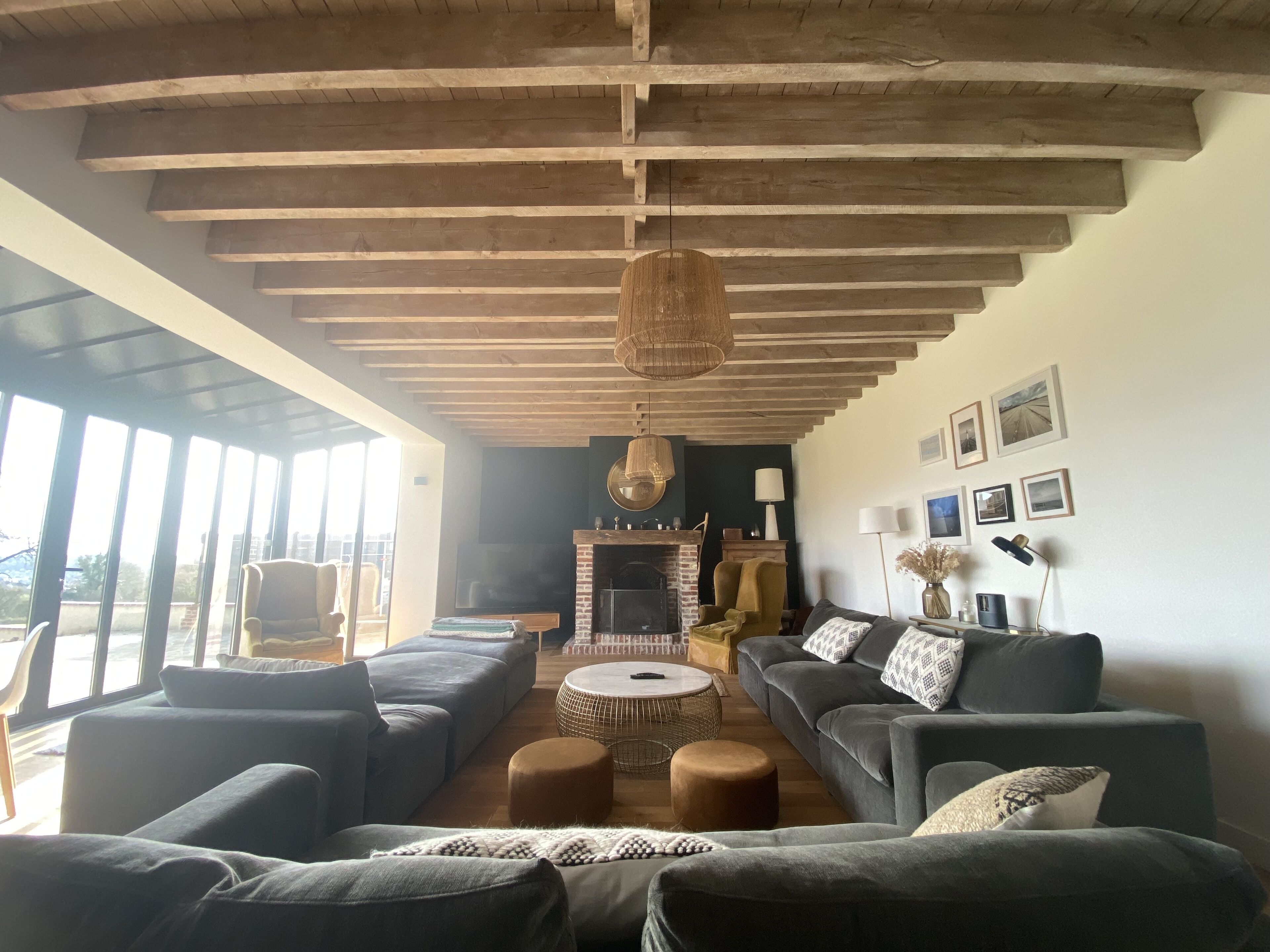 Un salon spacieux avec un haut plafond, de grandes fenêtres, une cheminée et un coin salon confortable.