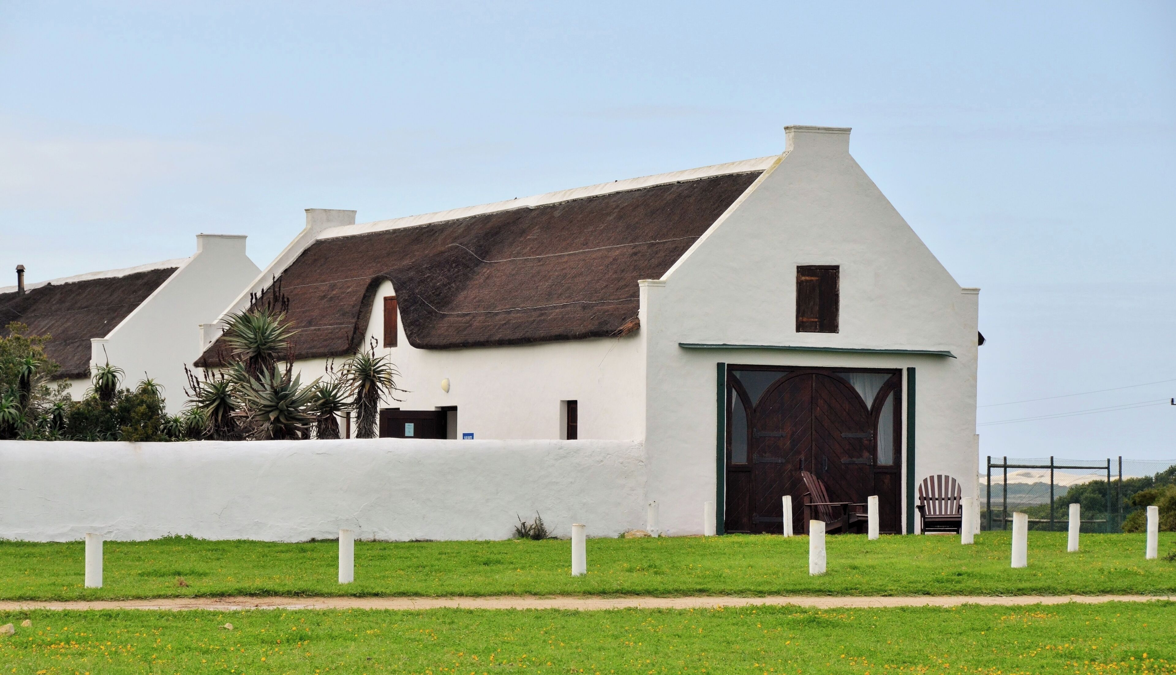 A building with a white exterior, a thatched roof, and a large wooden door.