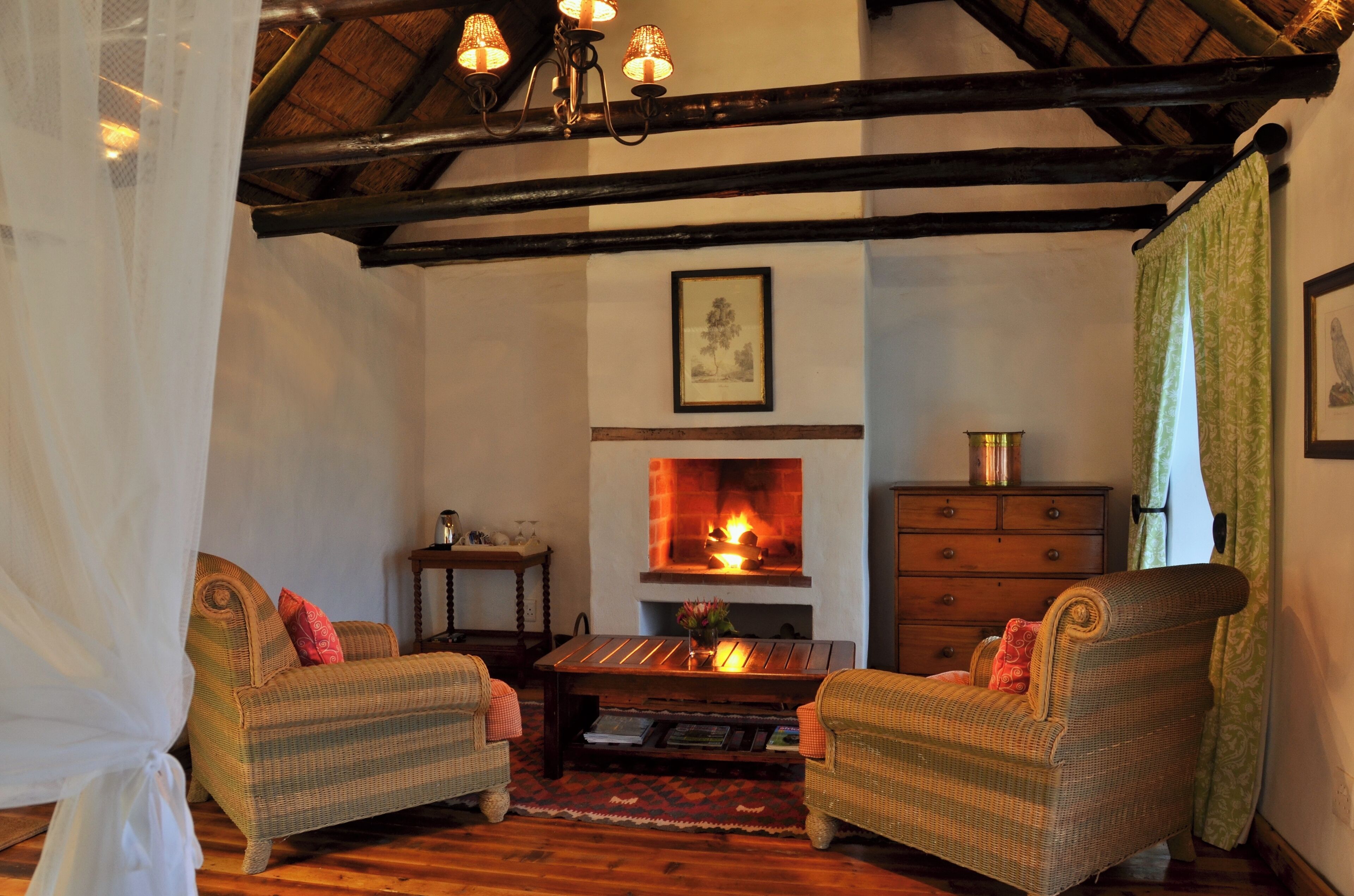 A cozy room with a fireplace, two wicker chairs, a wooden coffee table, and a dresser.