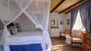 A bedroom with a canopy bed, a desk, and a chair.