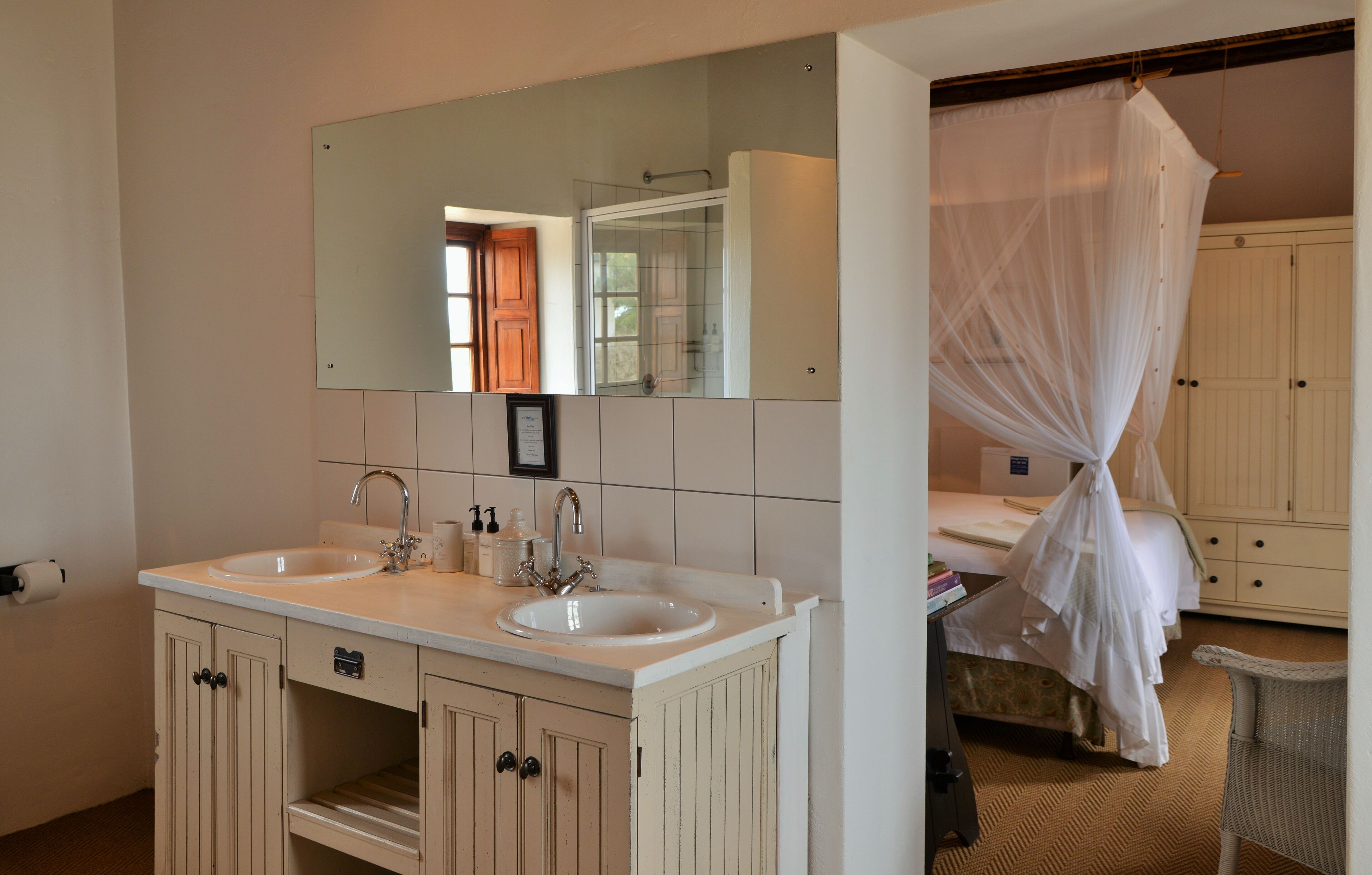 A bathroom with two sinks, a mirror, and a bed with a canopy.