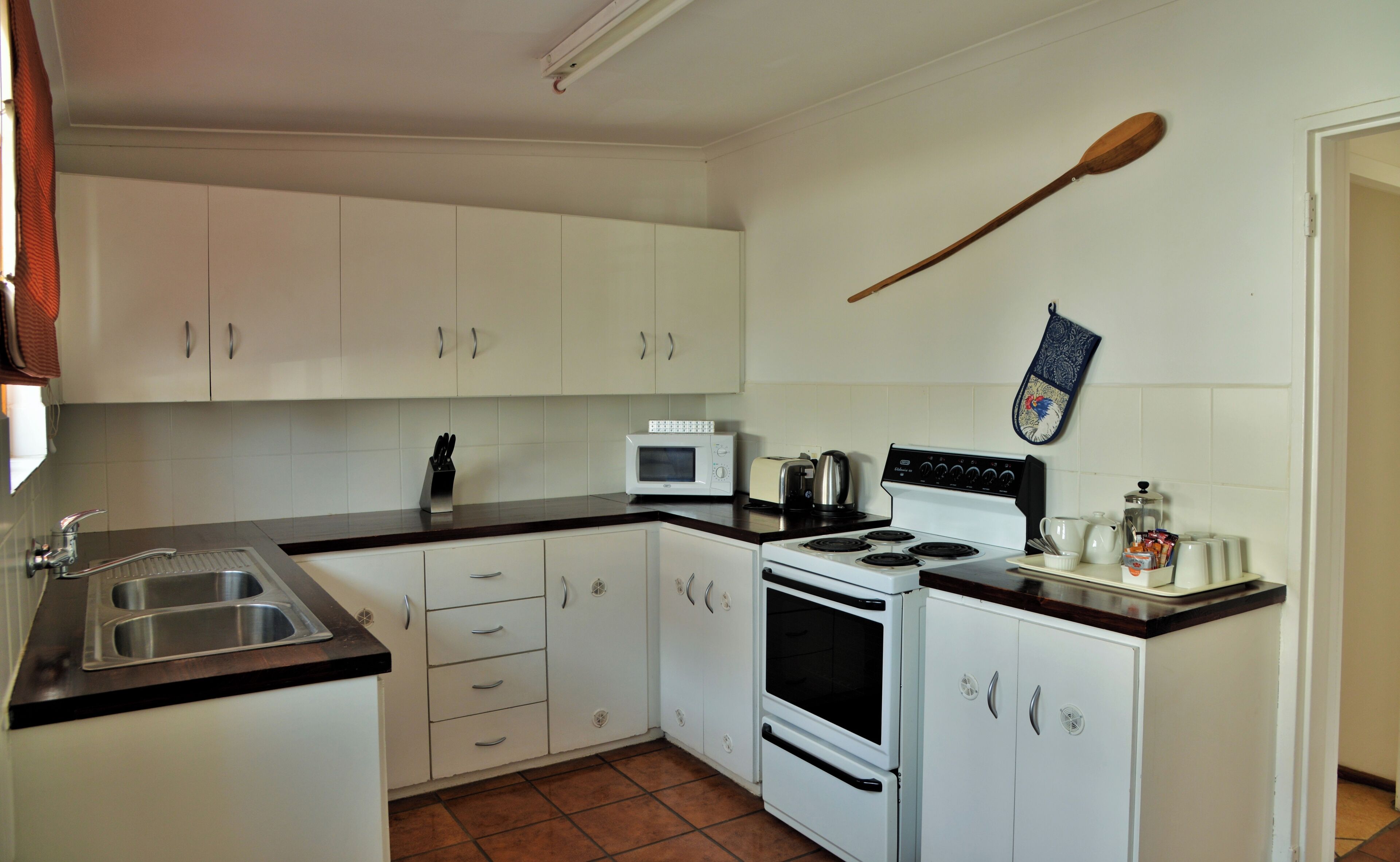 Una cocina compacta con armarios blancos, un microondas, una estufa y un lavabo.