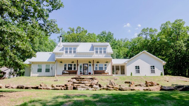 A two-story house with a front porch, a separate garage, and a stone retaining wall.