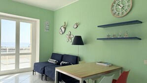 A room with a wooden table, two chairs, a sofa, a lamp, and decorative items on the wall. - N226 - Numana, wonderful two-room apartment facing the sea (Numana)