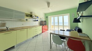A kitchen with a dining area, a ceiling fan, and a view of the beach. - N226 - Numana, wonderful two-room apartment facing the sea (Numana)