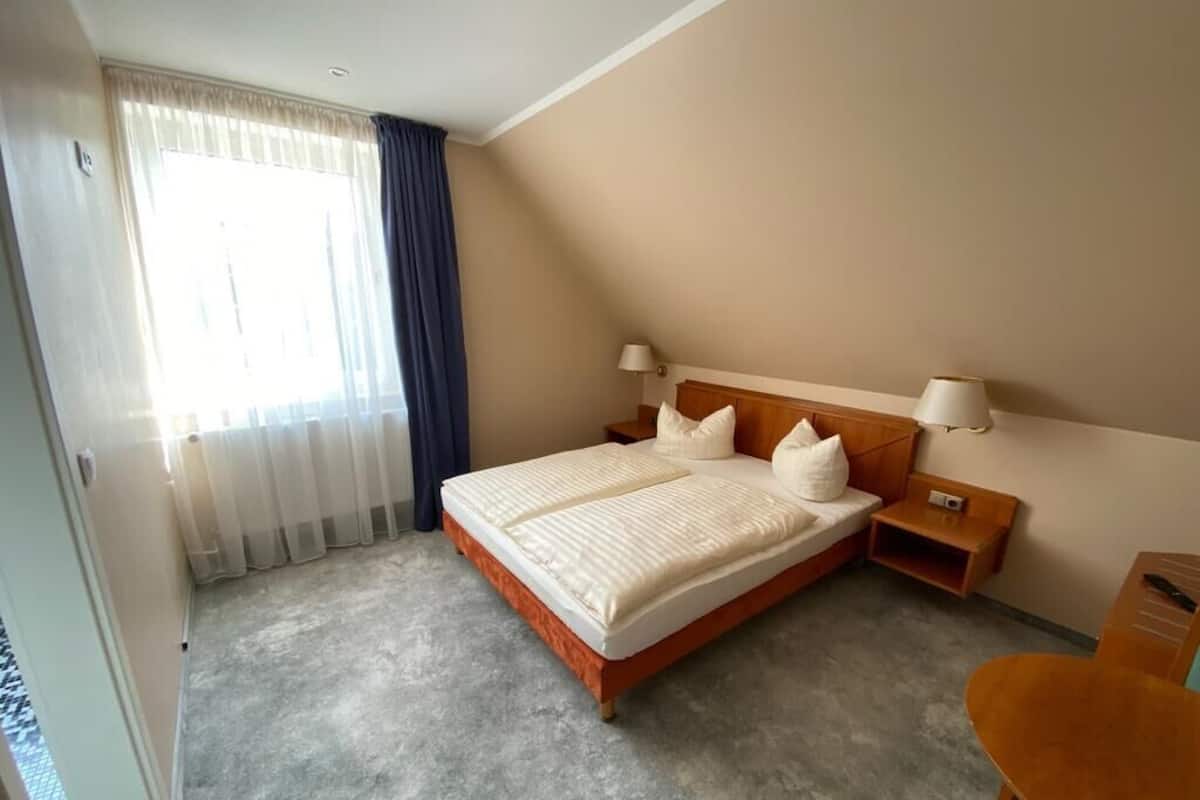 A hotel room with a large bed, two bedside tables, a desk, and a chair.