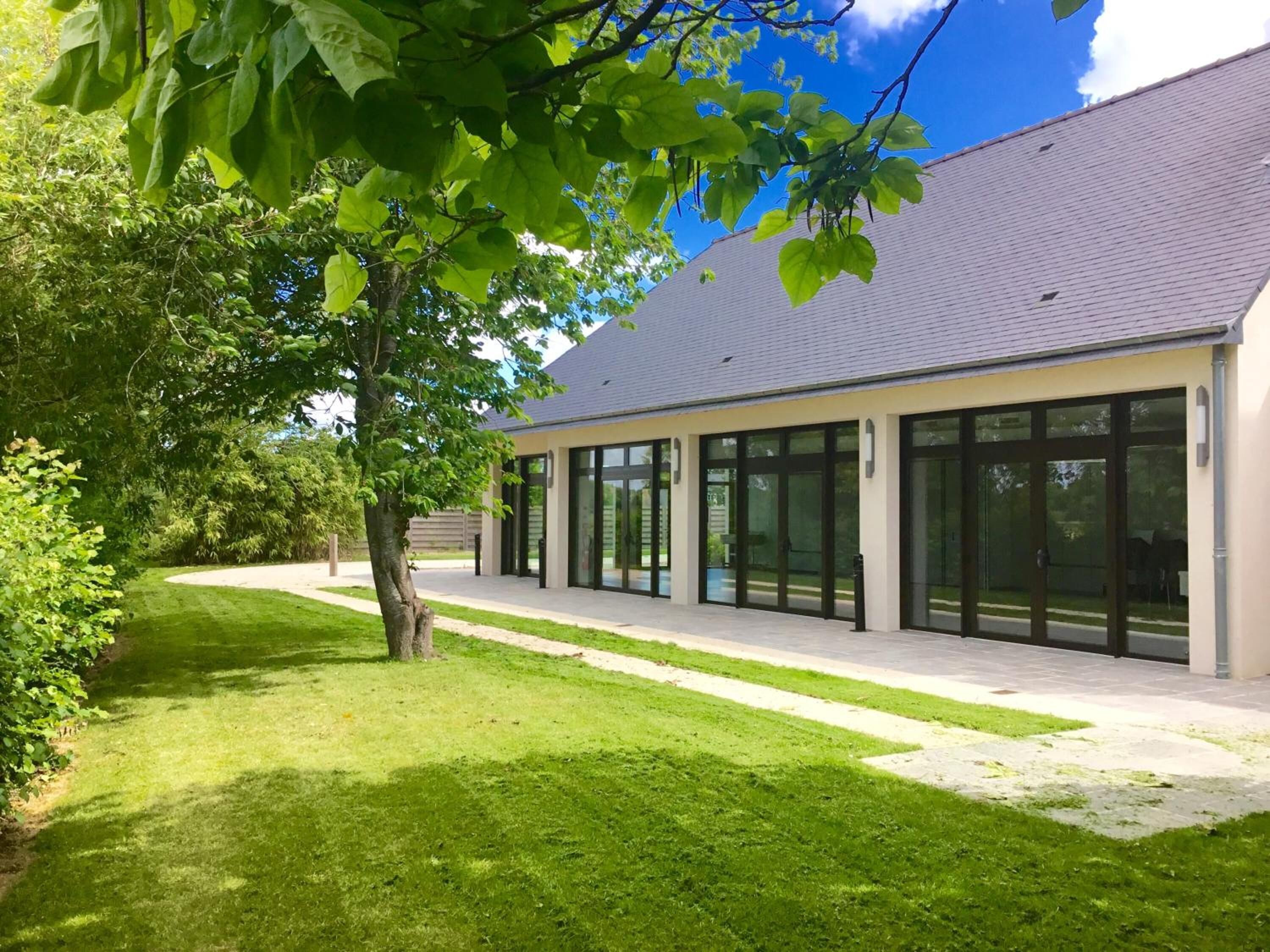 A modern building with large glass doors and a well-maintained lawn.
