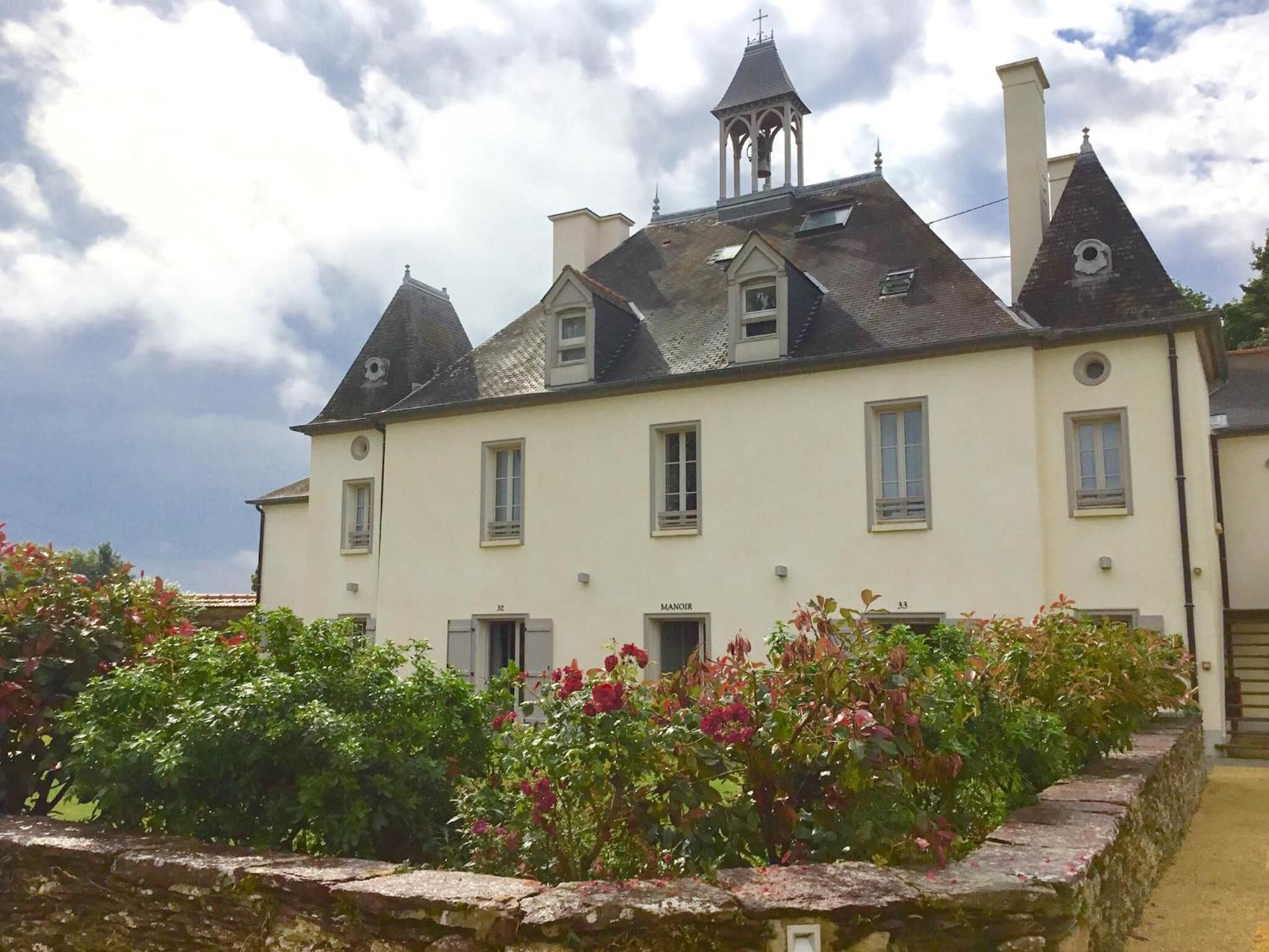 Un grand bâtiment à deux étages, doté d’une façade symétrique, de nombreuses cheminées et d’un clocher.
