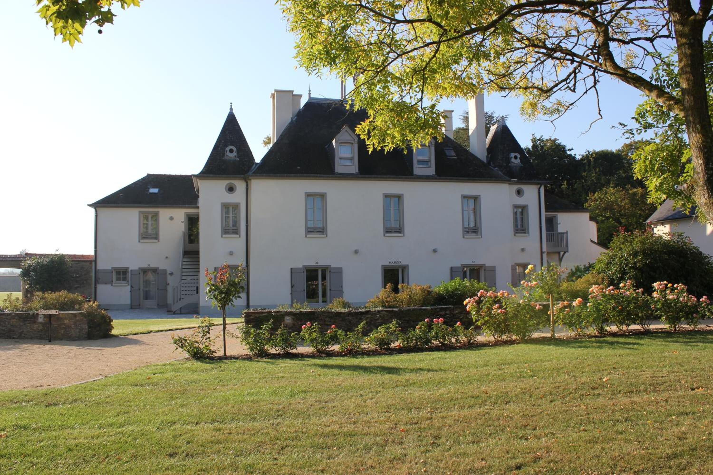 Un grand bâtiment blanc, doté de nombreuses cheminées et d’une façade symétrique.