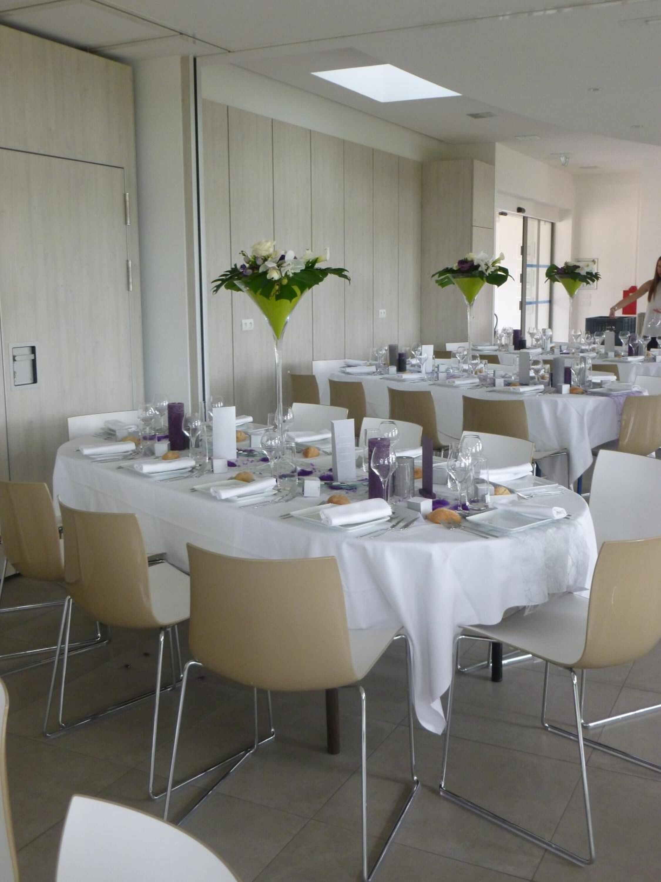 A banquet hall with round tables, white tablecloths, and beige chairs.