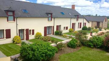 A row of two-story houses with dormer windows, a stone building, and well-maintained gardens.