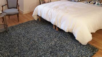 Un dormitorio con una cama, una silla, un cuadro enmarcado y una pared con estampado floral.
